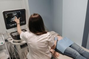 Médica realizando ultrassom morfológico em gestante, com a imagem do bebê na tela do aparelho
